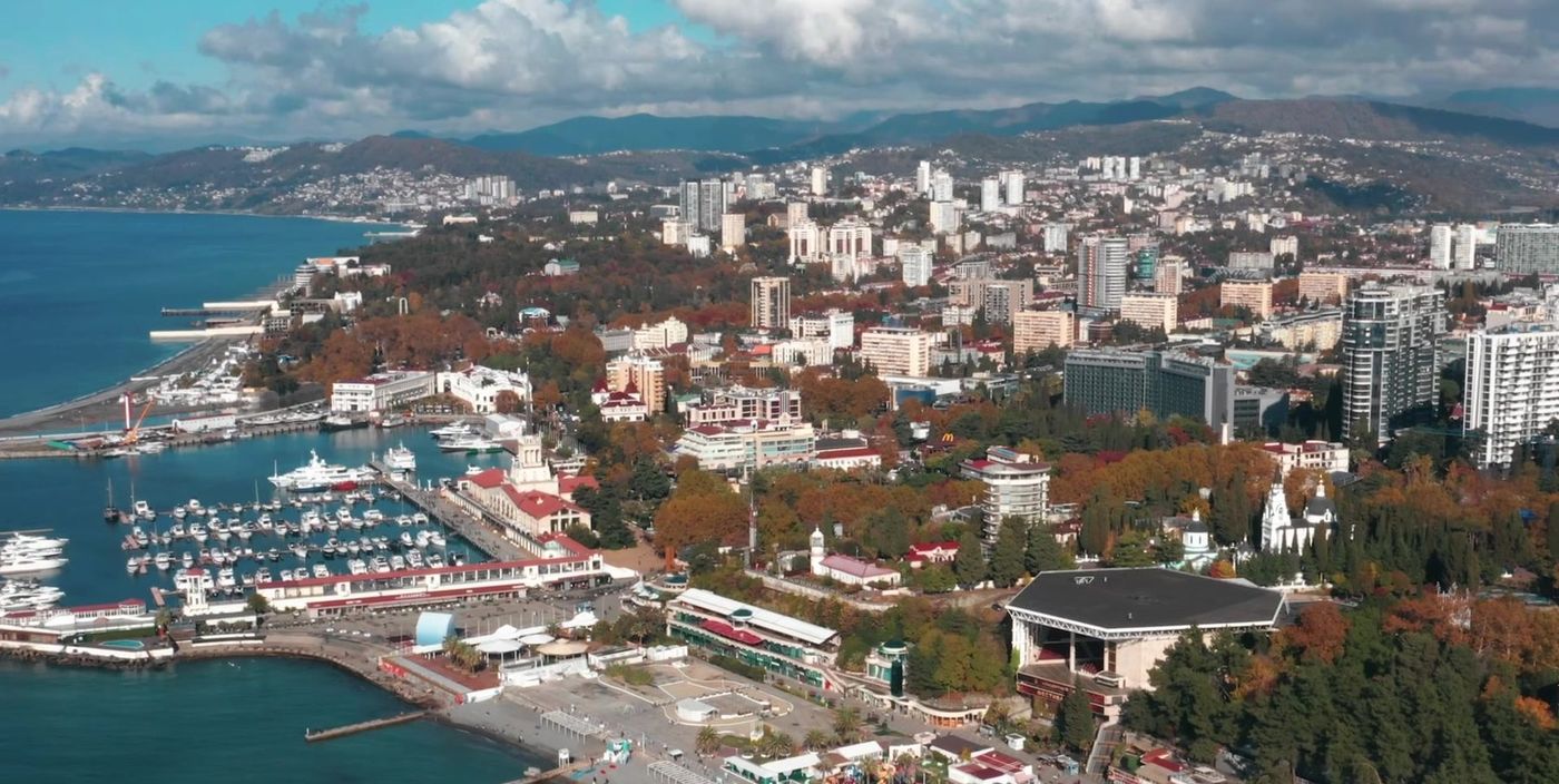 Вид с высоты на центр Сочи: морской порт, набережная, кварталы и горы на горизонте