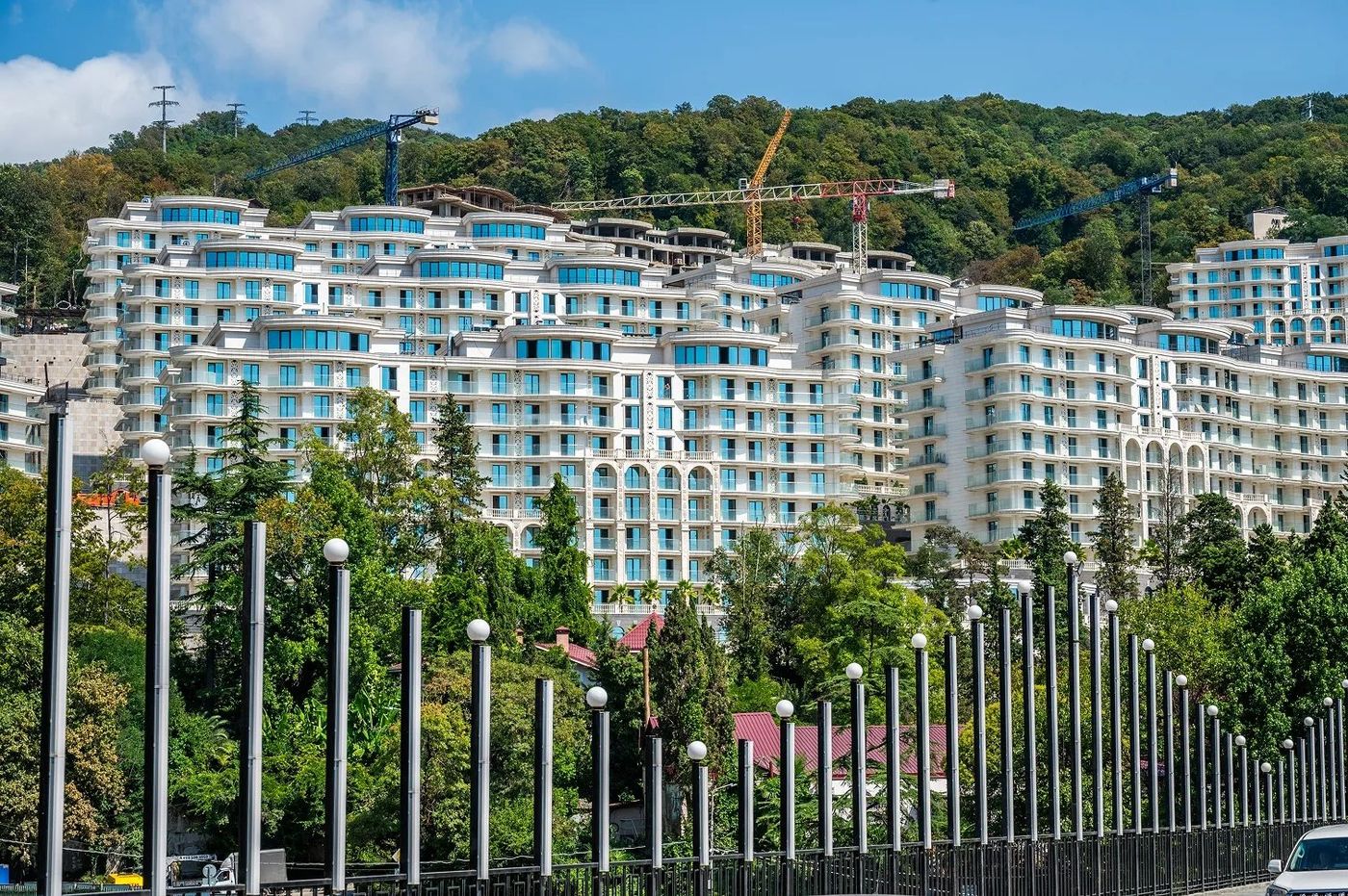 Корпуса Hotels & Resort на лесистом склоне, над ними строительные краны