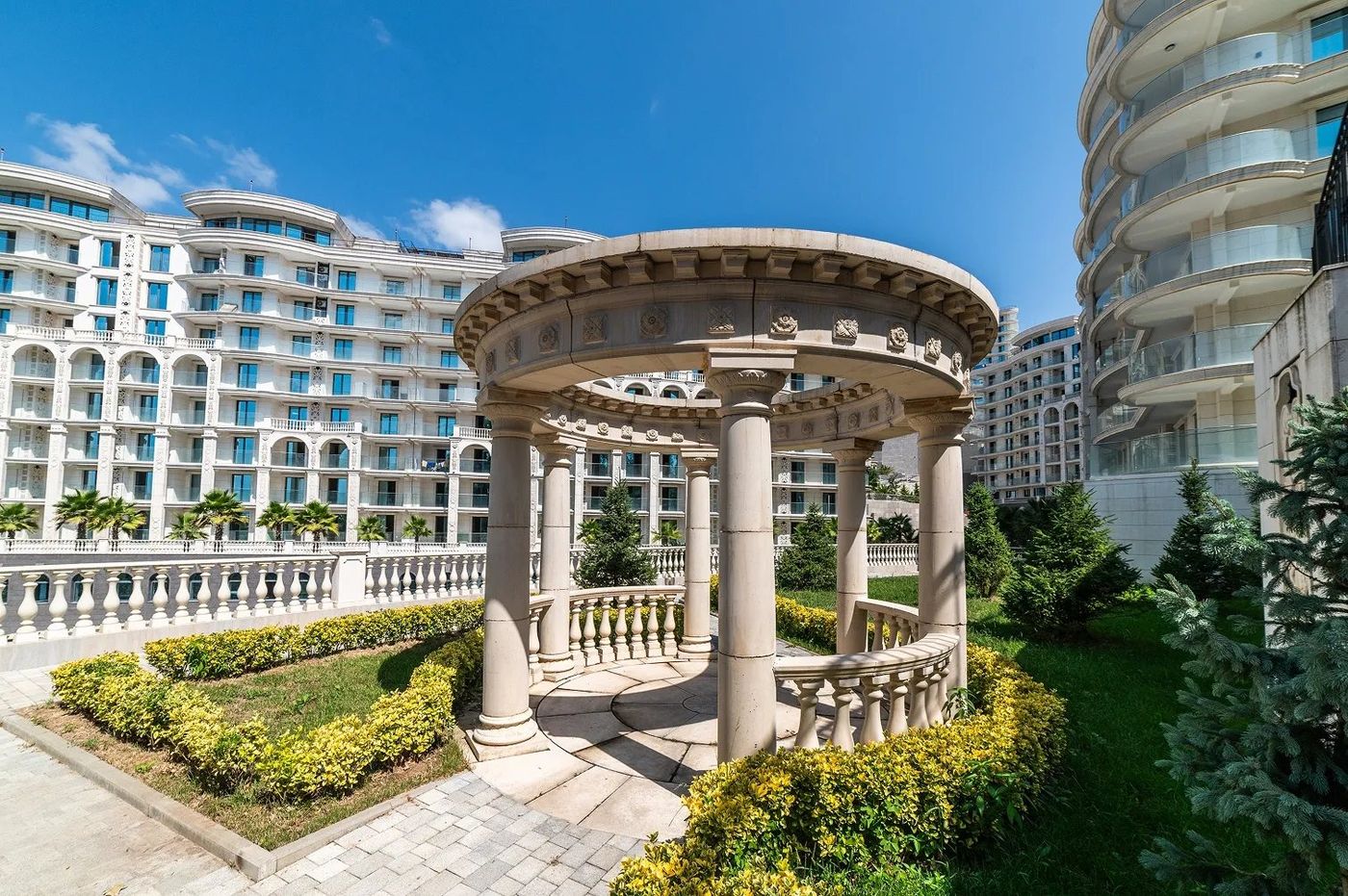Каменная ротонда с колоннами в саду перед белыми корпусами Hotels & Resort