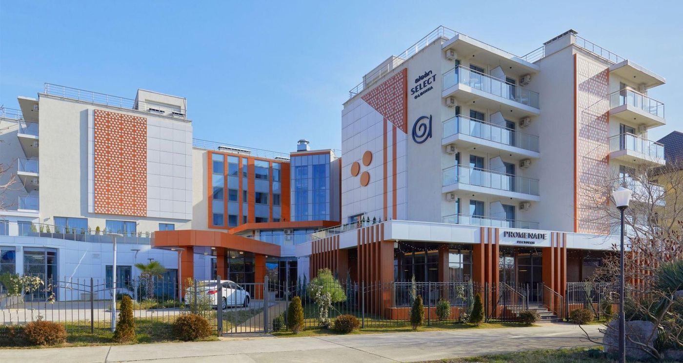 Корпуса отеля со стороны улицы: ограда, клумбы и соседние дома
