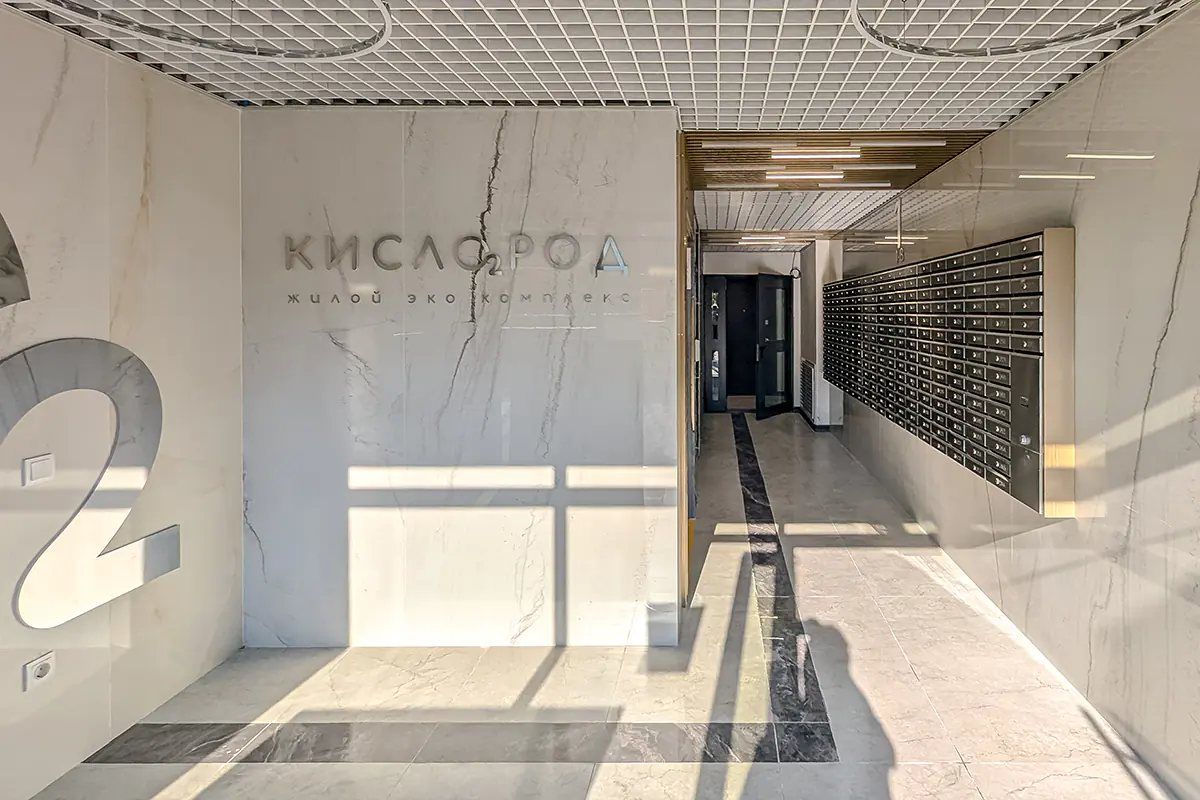 Входной холл с логотипом «Кислород» на стене и почтовыми ящиками вдоль прохода